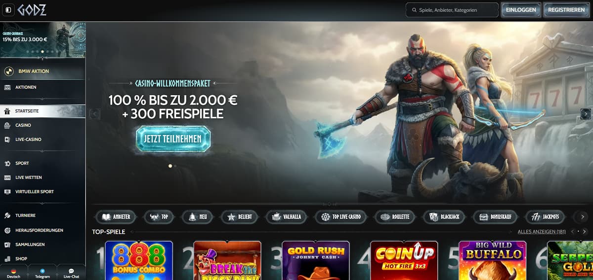 Godz Startseite mit Banner, das ein Willkommenspaket von 100 % bis zu 2.000 € plus 300 Freispiele bewirbt. Design im Mythologie-Stil mit Kriegerfiguren vor Bergen. Seitenleiste umfasst Casino, Live-Casino, Sportwetten und Turniere. Bereich zeigt Slots wie Break the Bank Again, Gold Rush Johnny Cash und Big Wild Buffalo. 